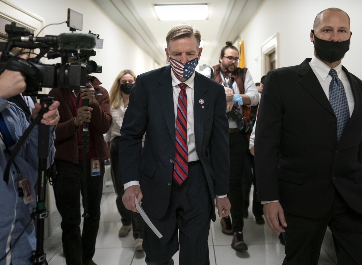 Congressman Paul Gosar walks in a hallway surrounded by reporters and cameras