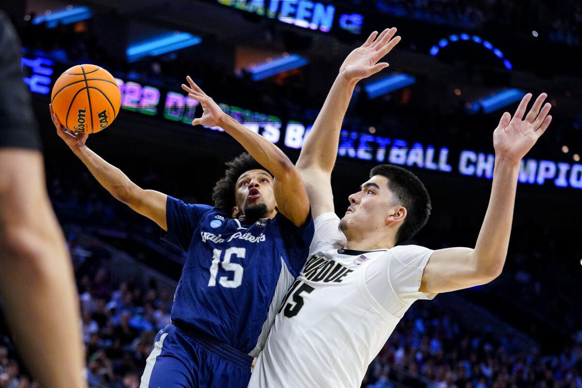 A basketball player tries to get a shot past a defender