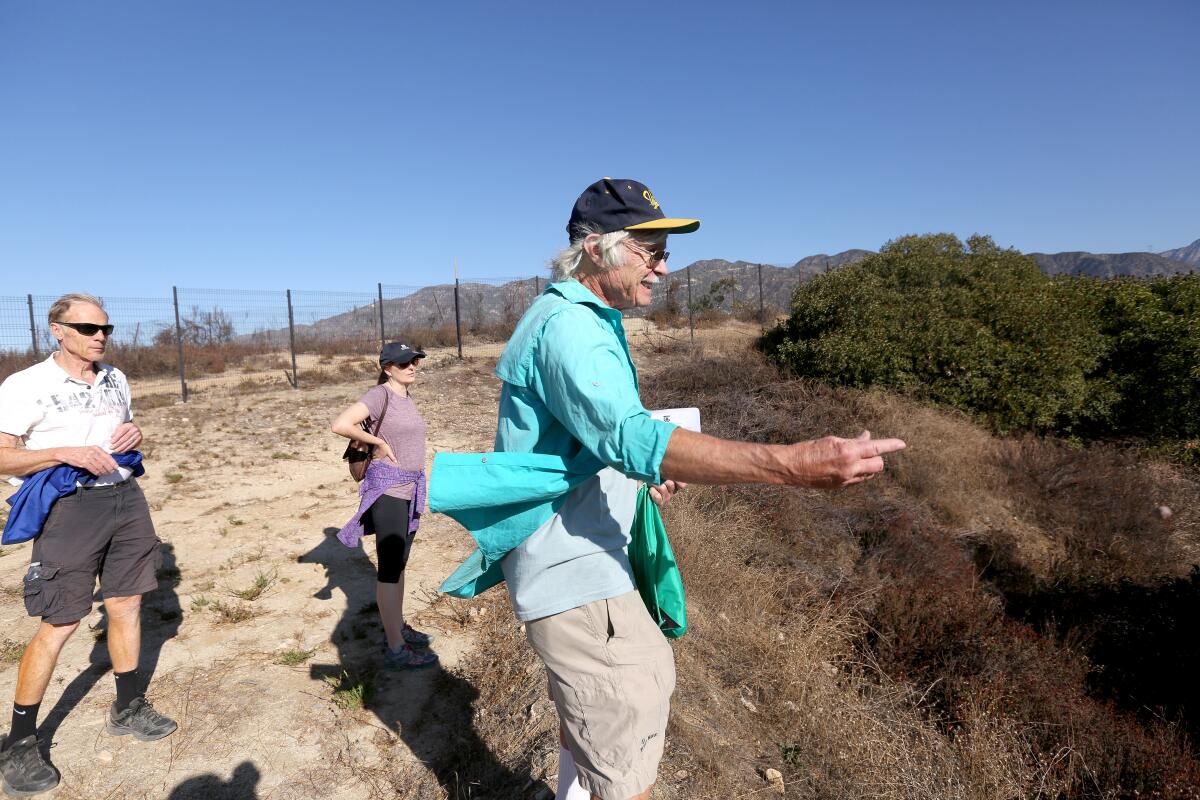 La Cañada Flintridge resident Terry Beyer throws seed balls into the brush during the fourth annual Mayor's Hike along a 1.5-mile part of the Descanso Trail, in La Cañada Flintridge on Saturday, Nov. 17, 2019.