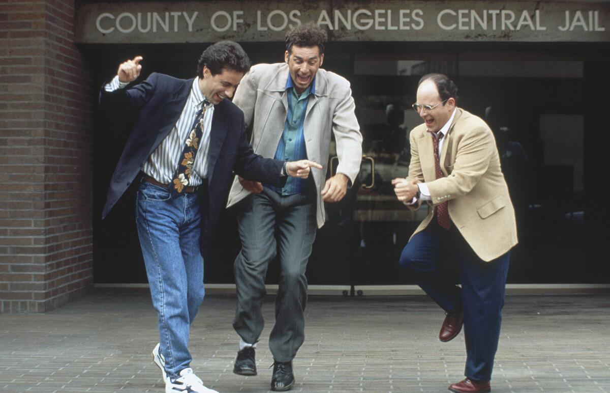 Three men in sport coats do a happy dance in front of a Los Angeles jail.
