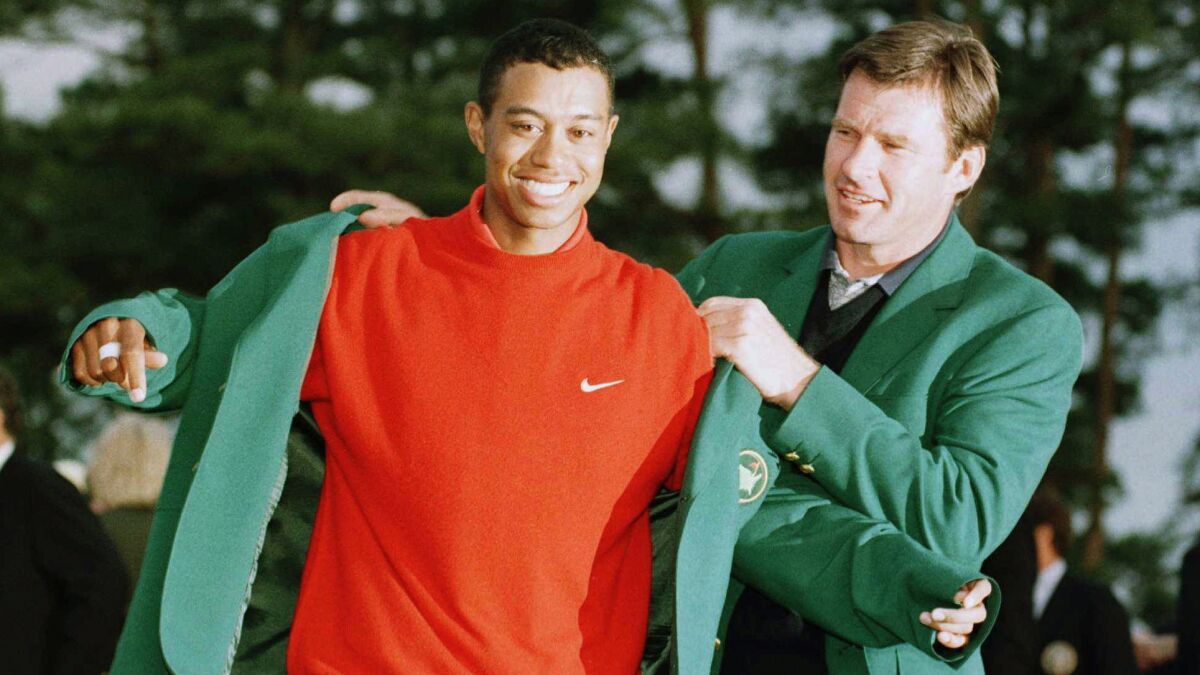 Nick Faldo helps Tiger Woods put on the green jacket following Woods' victory at the 1997 Masters.