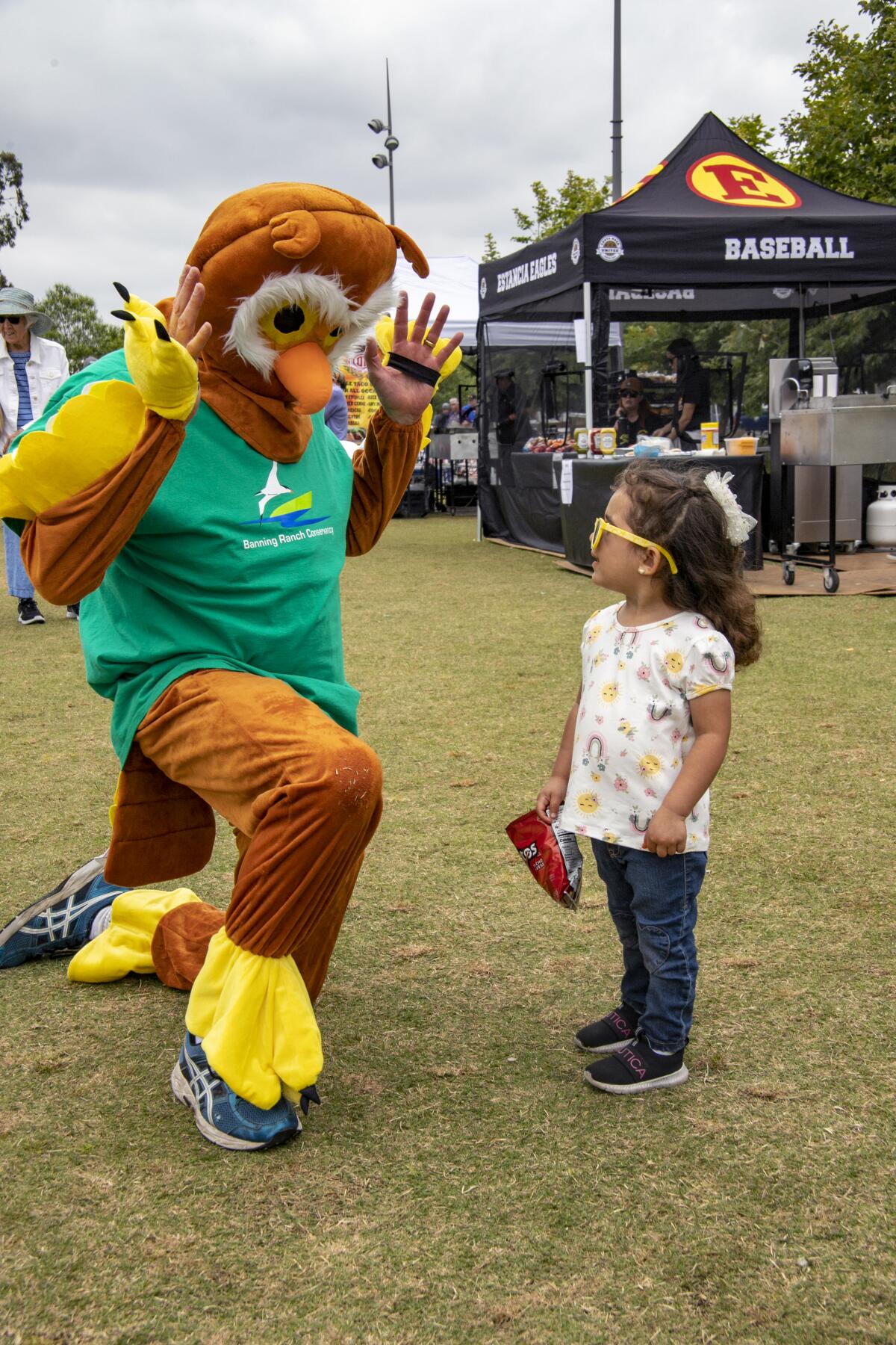 "Burrowing Owl" Terry Welch explains the preservation of Banning Ranch to Valentina Romo, 3, at the Fish Fry in Costa Mesa. 