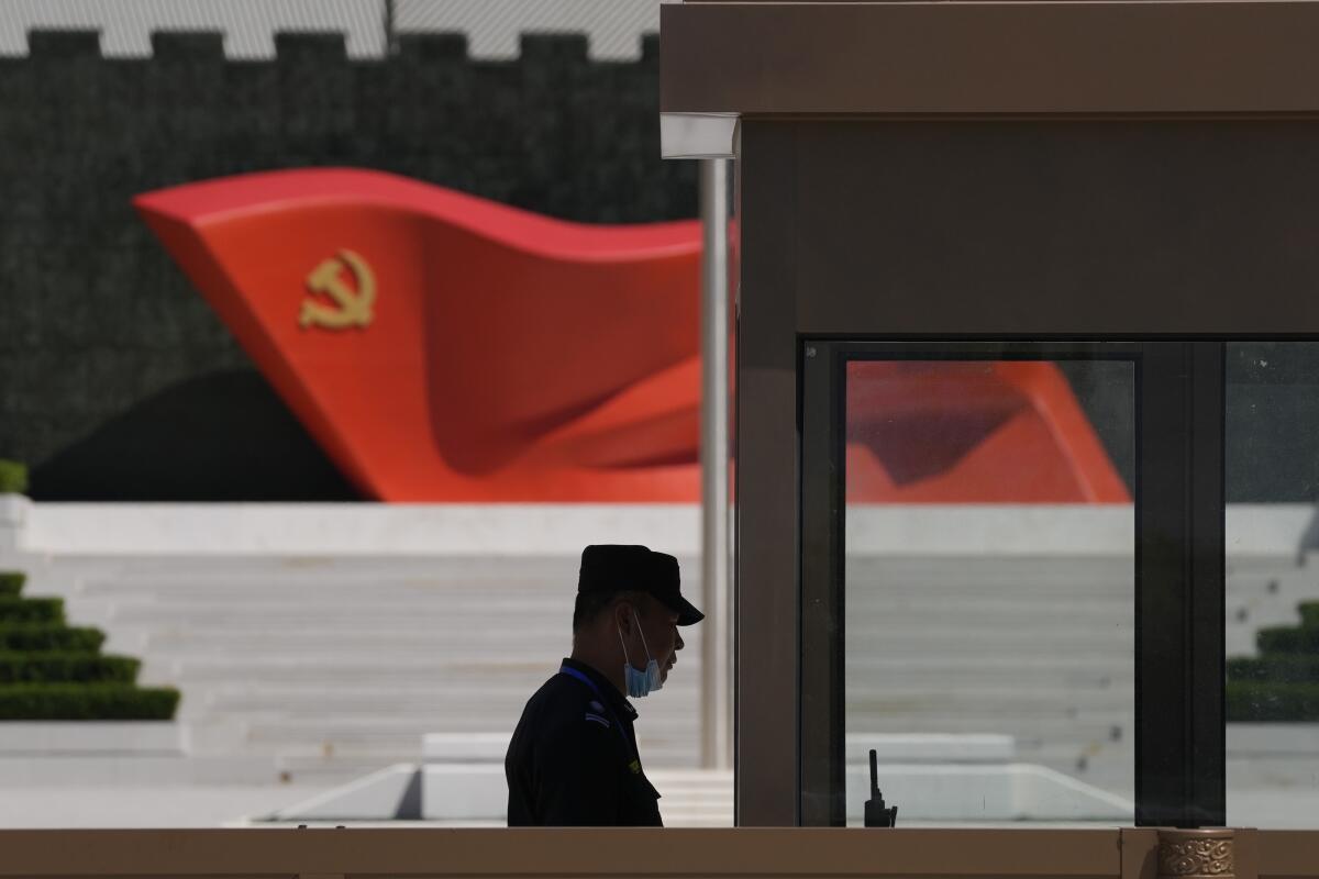 Silhouette of security guard near sculpture of Chinese Communist Party flag