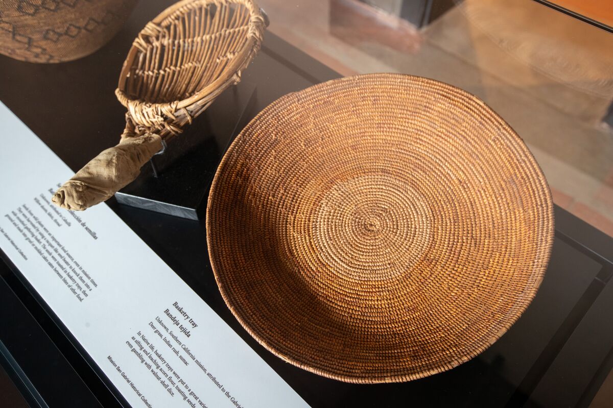 Two examples of Native American basketry are placed next to each other inside a case.