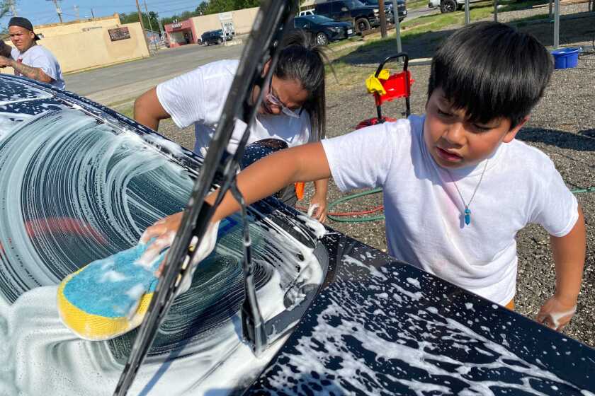 Nahum Gonzalez, 10, in the fourth grade, and his mother Betsy chip in at a pop-up car wash on Thursday May 26, 2022 to raise funds for the families of the 19 children and two teachers killed in a shooting at Nahum's former school, Robb Elementary, on Tuesday. (Kevin Rector / Los Angeles Times)