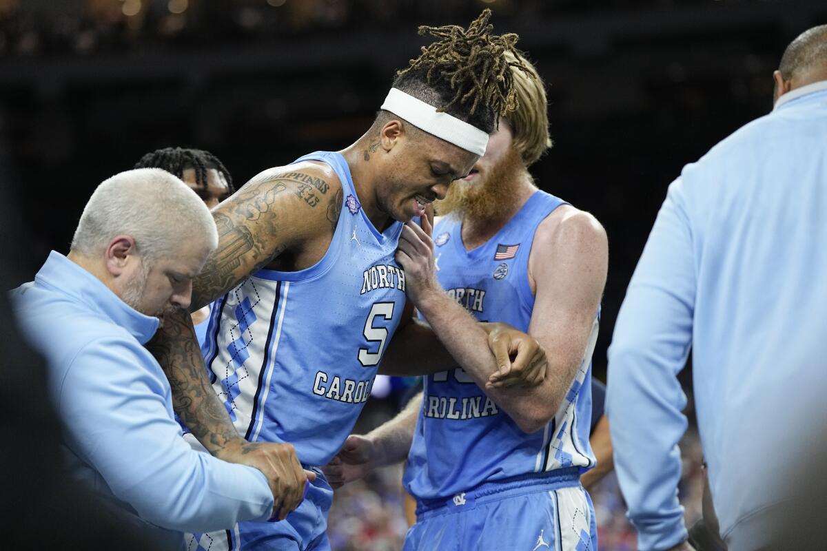 North Carolina forward Armando Bacot is helped off the court during the second half of a college basketball game against Duke in the semifinal round of the Men's Final Four NCAA tournament, Saturday, April 2, 2022, in New Orleans. (AP Photo/David J. Phillip)