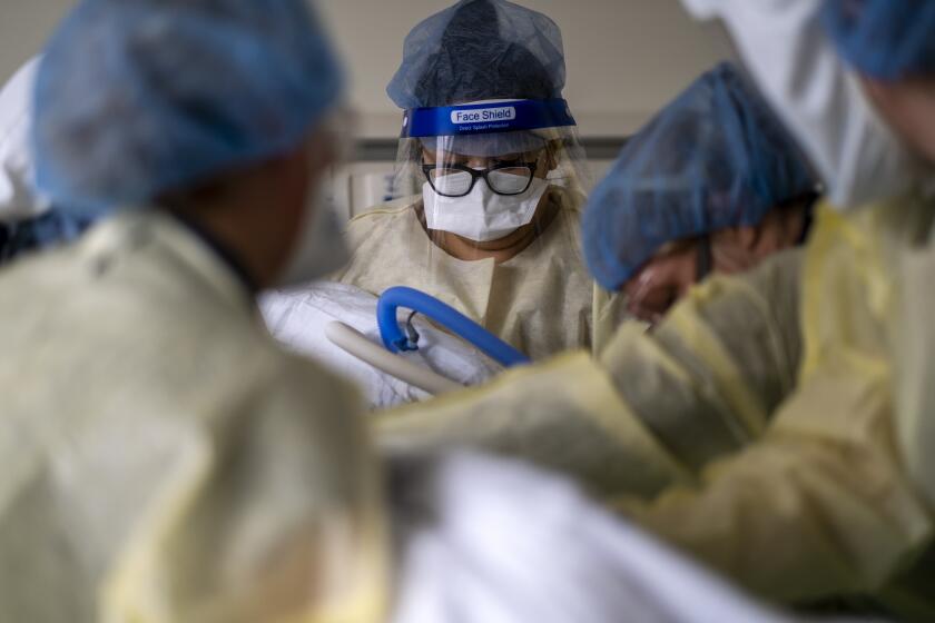 VENTURA, CA - SEPTEMBER 08: Brianna Corres, 28, middle, holds her brother's hand as the nursing team repositions him inside the ICU Ventura County Medical Center - a hospital in the city of Ventura, on Wednesday, Sept. 8, 2021 in Ventura, CA. Today the hospital reports they have 22 covid19 posstive patients plus 3 under investigation. Of those cases, 4 are reported vaccinated and 2 are partially vaccinated and 16 are unvaccinated. (Francine Orr / Los Angeles Times)