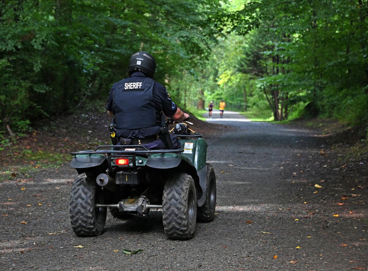 A Harford County deputy patrols the trail in Bel Air, Md., where the body of Rachel Morin was found on Aug. 6.