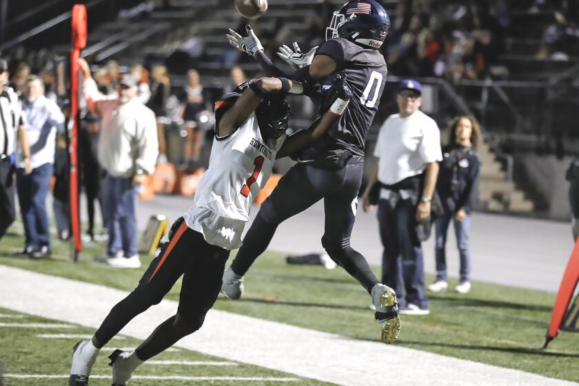 Newport Harbor's Jordan Anderson (0) leaps over Haston Allen (1) or a touchdown catch during Sunset League opener against Huntington Beach on Friday.