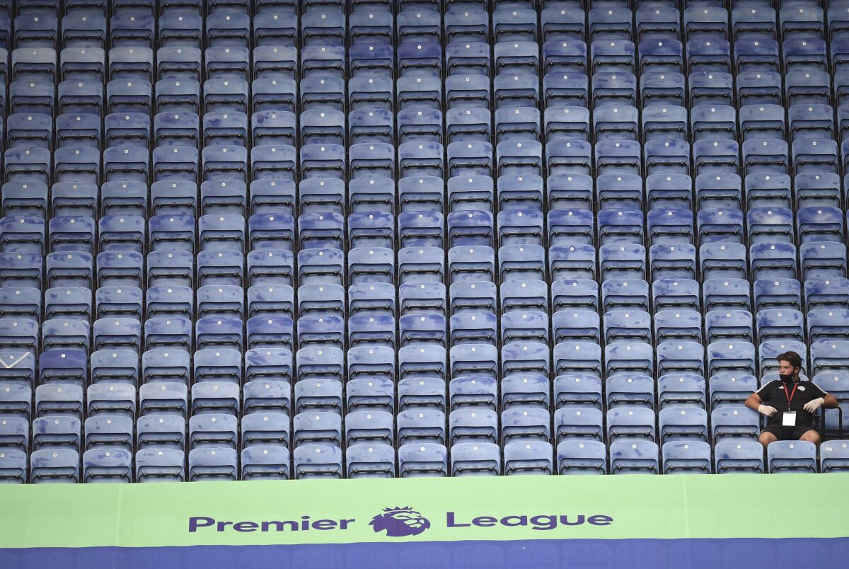A steward wearing a face mask sits on empty stands during the English Premier League soccer match between Leicester City and Manchester United at the King Power Stadium, in Leicester, England, Sunday, July 26, 2020. (Oli Scarff/Pool via AP)
