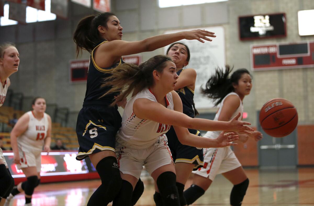 Huntington Beach's Alyssa Real, center, makes a pass after securing an offensive rebound against Sonora's Lizbeth Gomez, left, during the first half in the Matt Denning Classic at Mater Dei High on Saturday.
