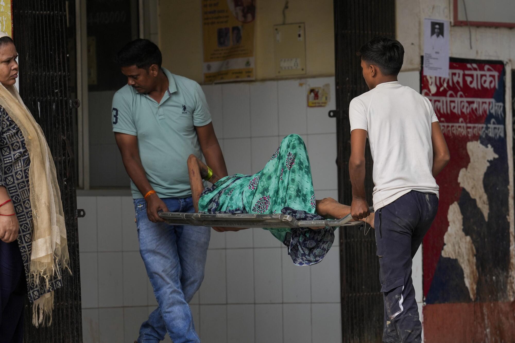 An elderly woman is carried on a stretcher into a hospital in India.