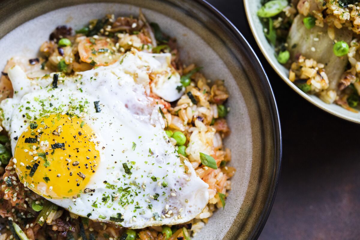 This image released by Milk Street shows a recipe for Kimchi and bacon fried rice, topped with a fried egg and sprinkled with furikake. (Milk Street via AP)
