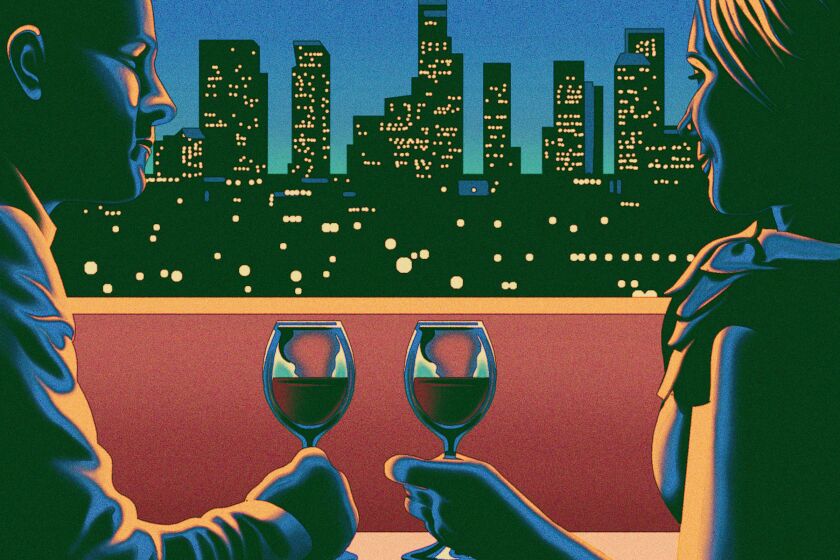 Man and woman drink wine in front of the Los Angeles skyline.