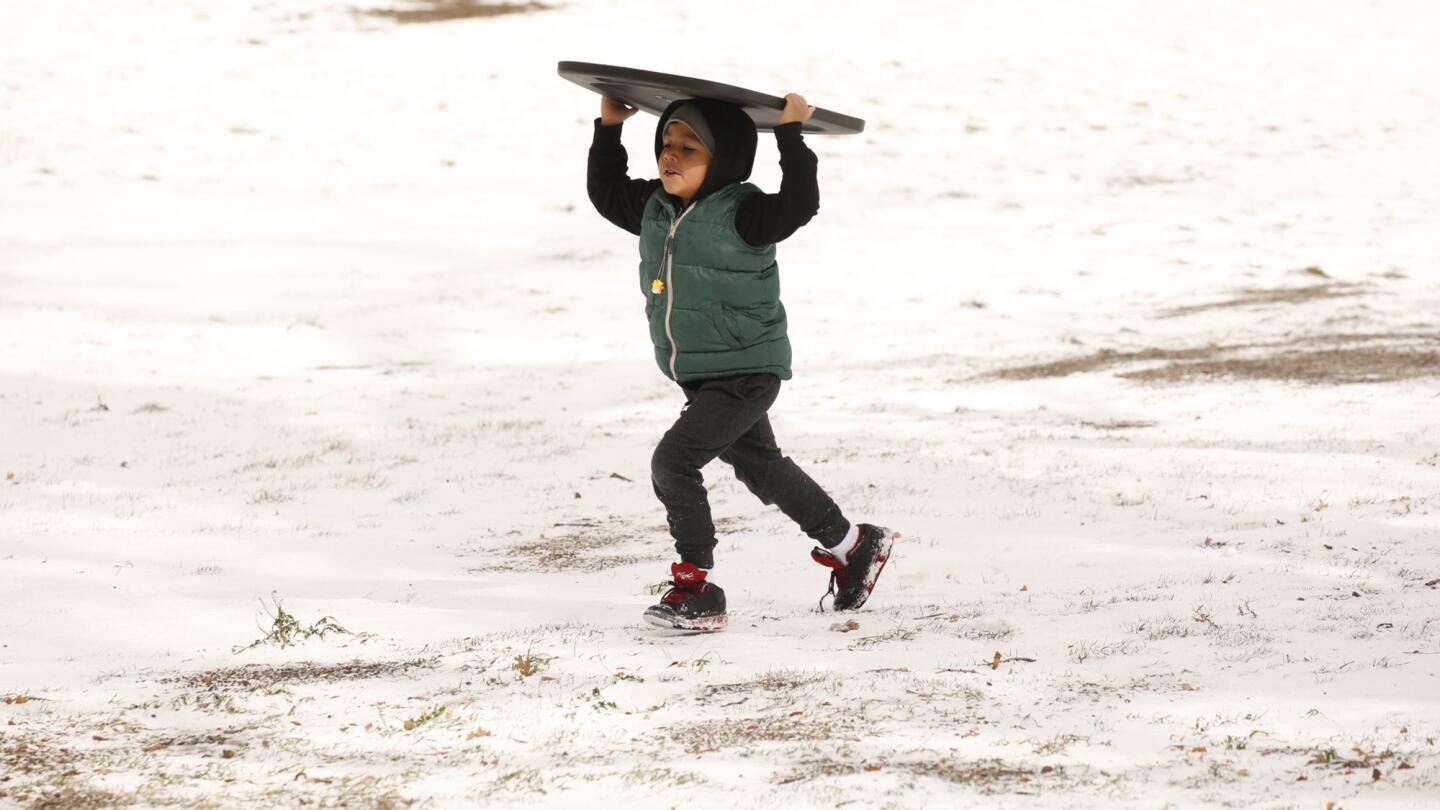 Edgar Reyes, 6, uses the lid of a container to slide down snow-covered hills in Frazier Park as his family visits from Bakersfield on Monday.