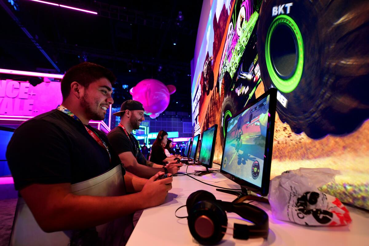 People sit in a row playing  video games at a large interactive gathering