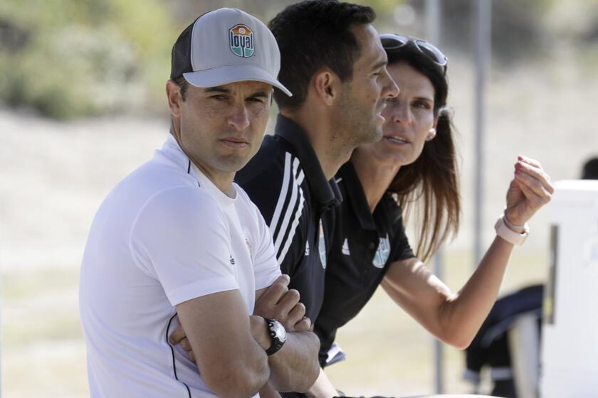 Landon Donovan, left, wears a baseball cap with his arms folded  while sitting next to his San Diego Loyal assistant coaches