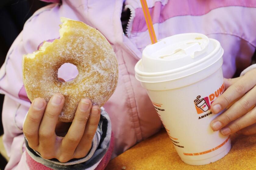 A girl holds a doughnut and a beverage at a Dunkin' Donuts in New York. A Santa Monica location of the doughnut chain is scheduled to open Sept. 2.