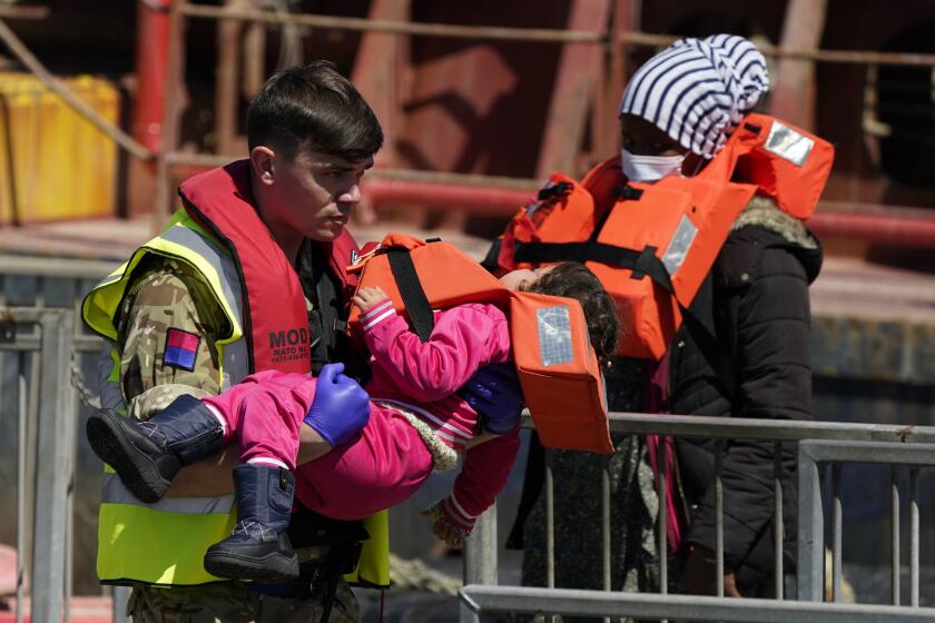 A soldier carries a child from a group of people thought to be migrants are brought in to Dover, England, by Border Force, following a small boat incident in the Channel, Tuesday June 14, 2022. (Andrew Matthews/PA via AP)