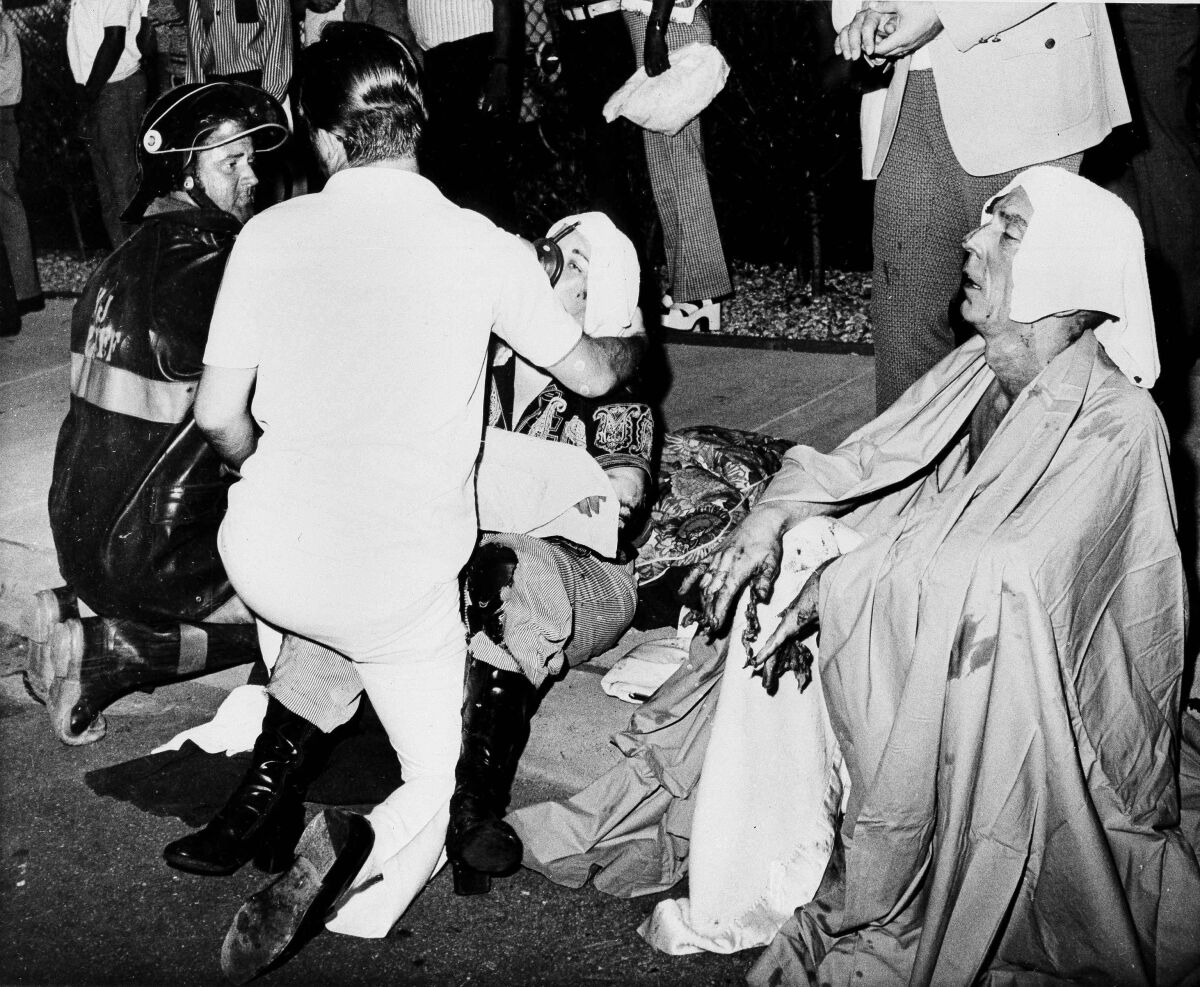 FILE - Firemen give first aid to survivors of a French Quarter fire that swept through a second story bar leaving 32 dead and 15 injured, June 25, 1973, in New Orleans. Nearly a half-century after arson killed 32 people in a New Orleans gay bar, the City Council has renewed the search Thursday, Aug, 4, 2022, for the remains of four victims, including three who were never identified. (AP Photo/G.E. Arnold, File)