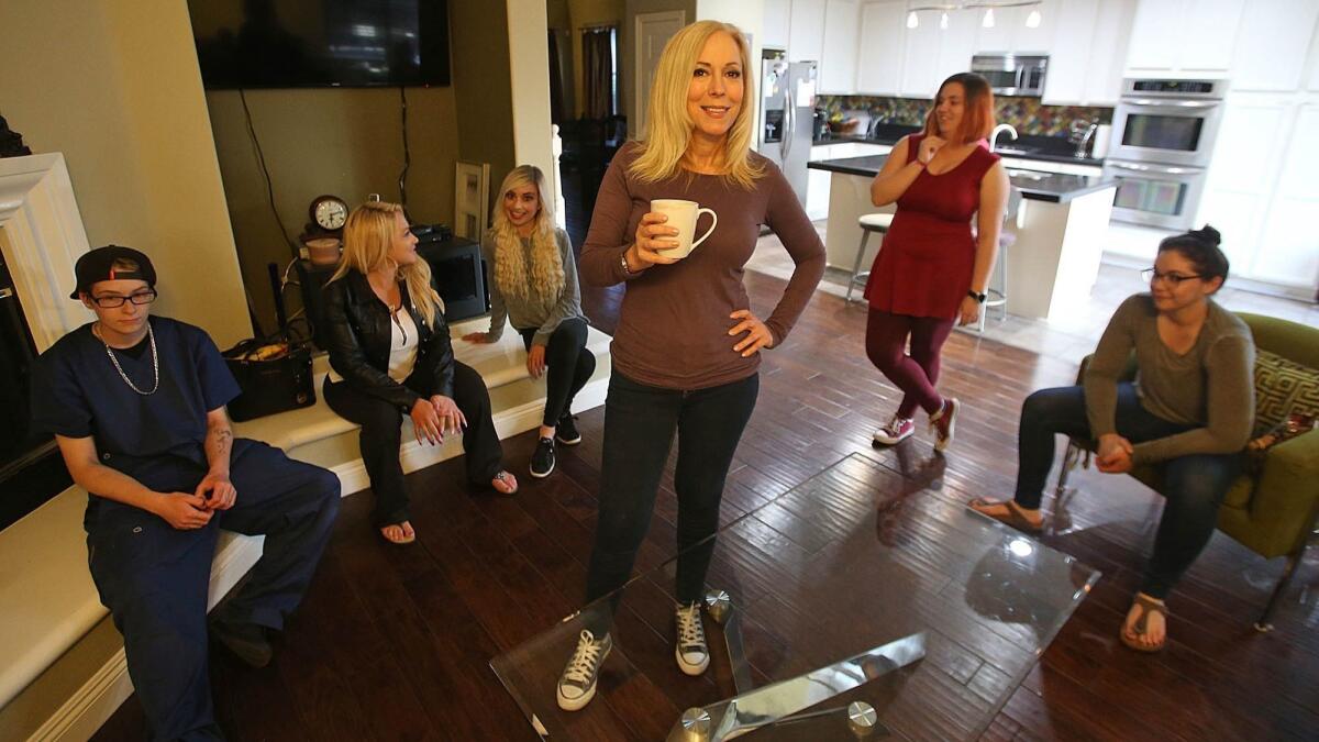 Lauri Burns has coffee and chats with former foster kids in the living room of her house..