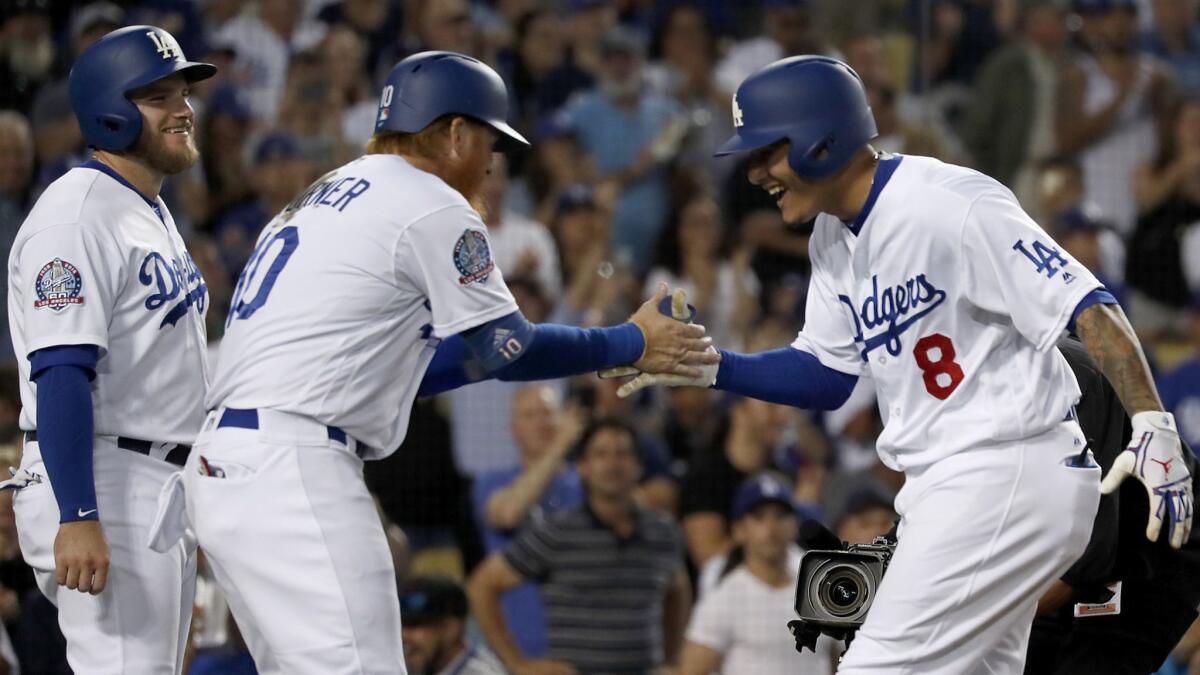 Dodgers shortstop Manny Machado, right, is congratulated by teammates Max Muncy, left, and Justin Turner after hitting a three-run home run against the Padres in the third inning on Saturday.