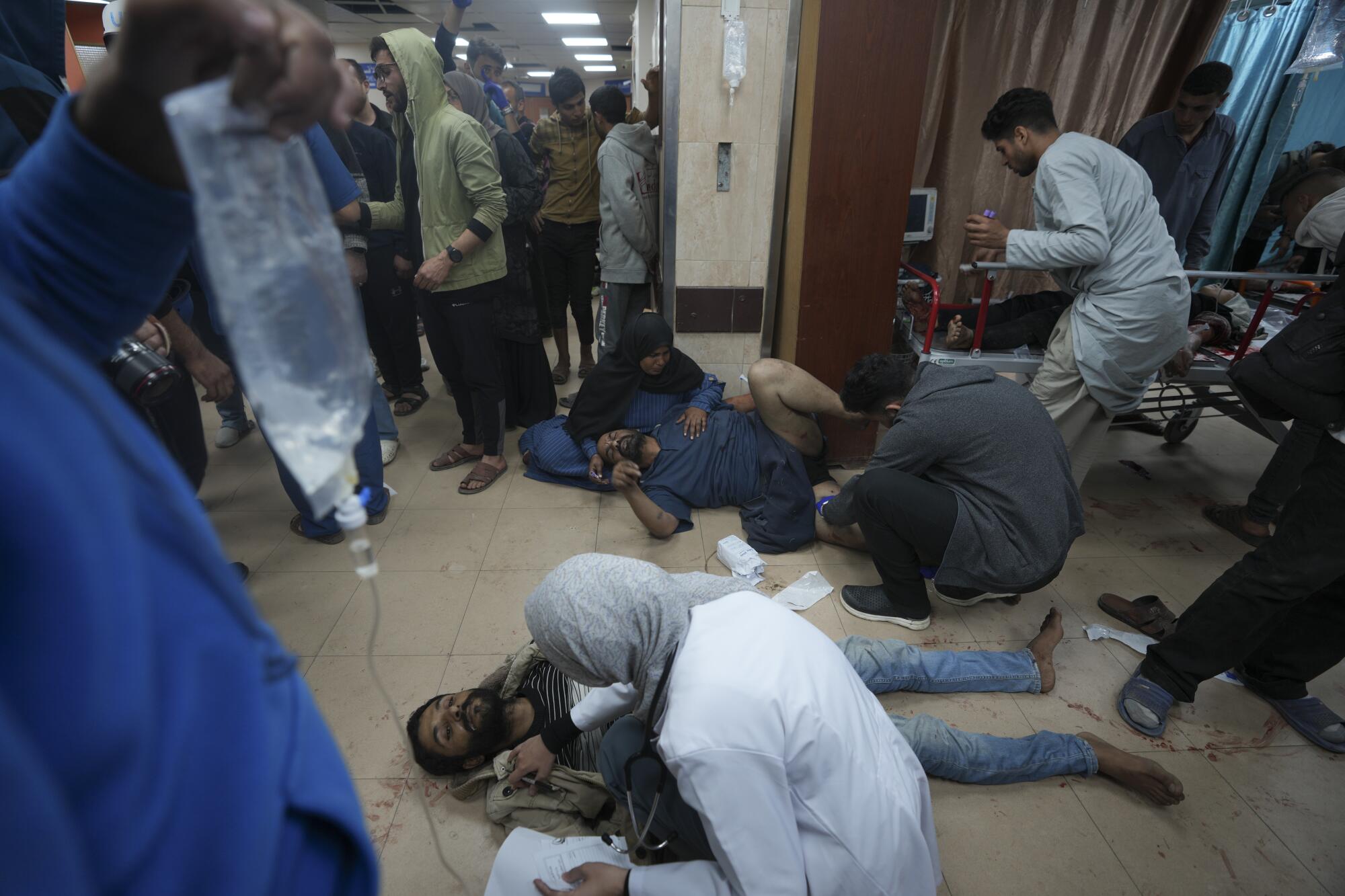 Wounded Gazans sit and lie on the floor at a crowded hospital