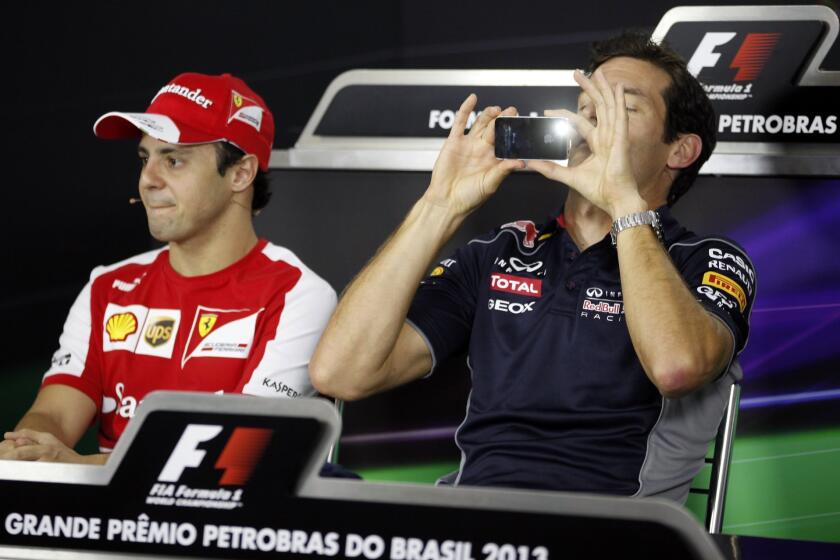 Red Bull Formula One driver Mark Webber (R) of Australia takes a photograph next to Ferrari Formula One driver Felipe Massa of Brazil before a news conference ahead of the Brazilian Grand Prix.