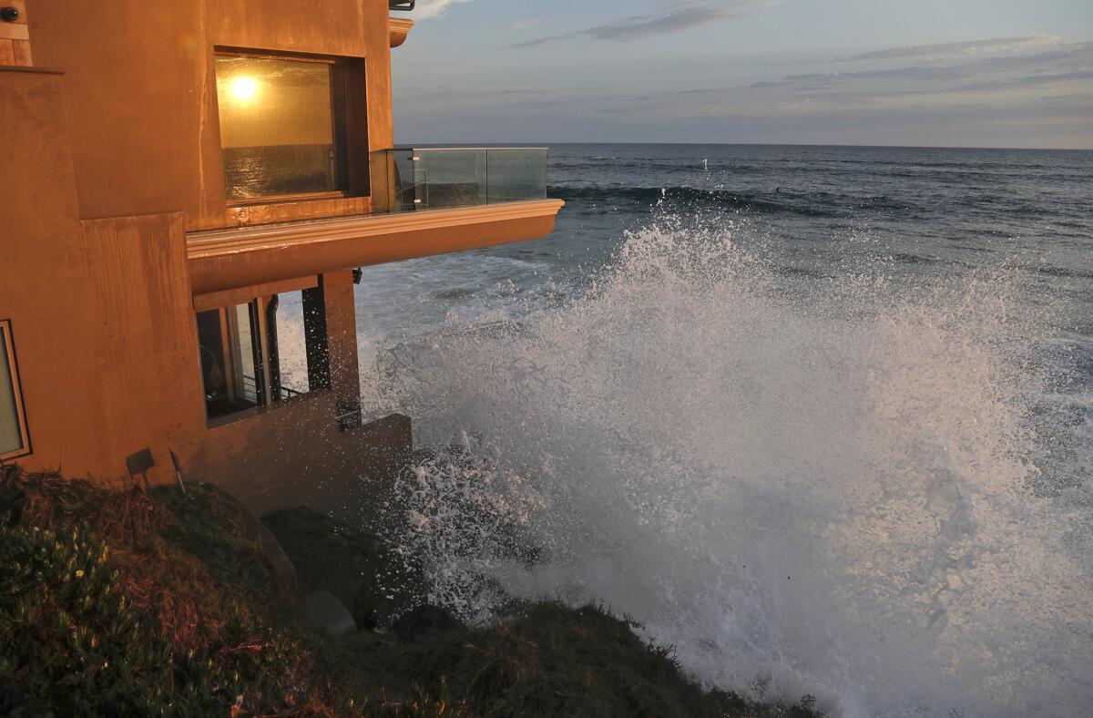 A high tide wave crashes below a beach front home in Laguna Beach on Tuesday.