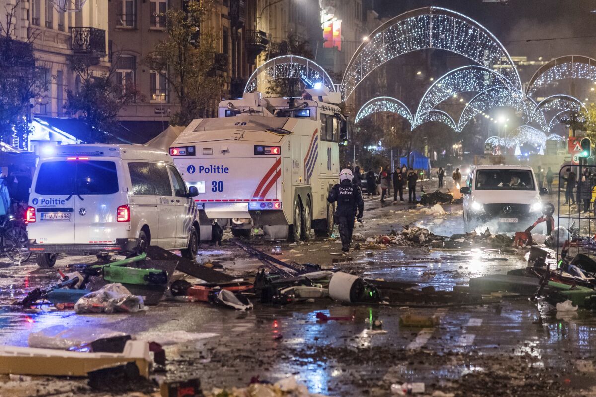 Police cars drive through a debris covered boulevard in Brussels