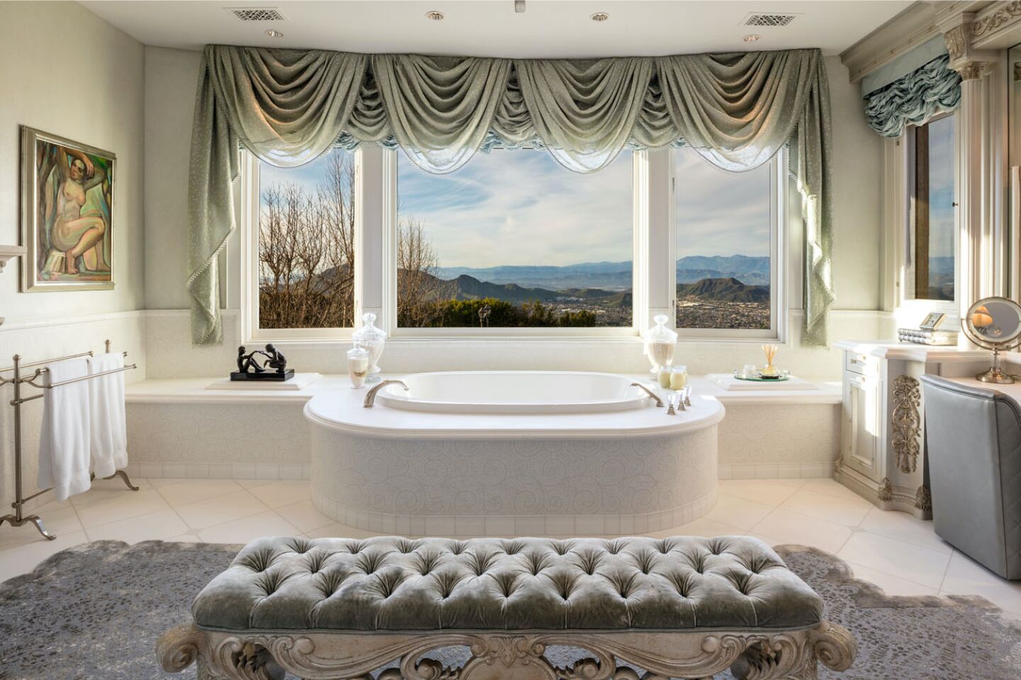 A tub dominates the primary bathroom, with large window, vanity area and fireplace.