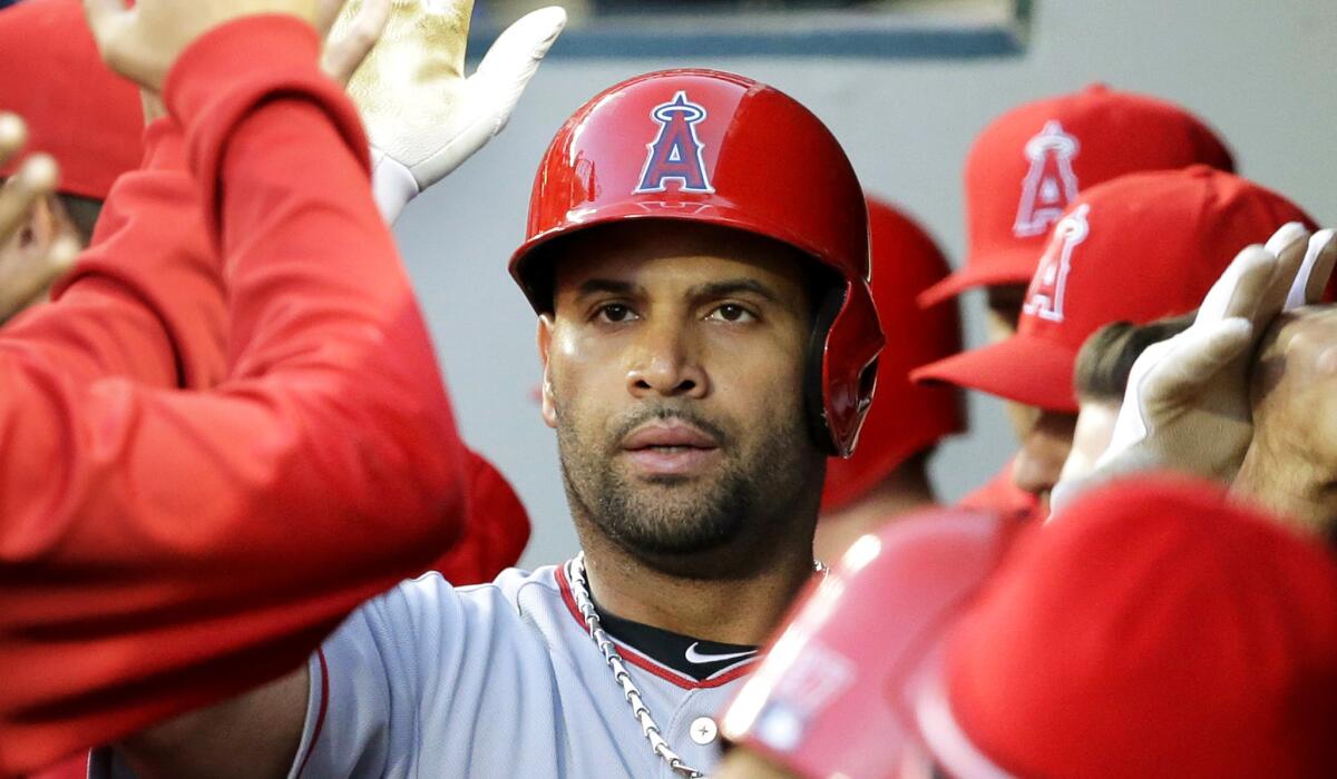 Angels first baseman Albert Pujols is greeted by teammates in the dugout after he hit his 521st career home run Wednesday.