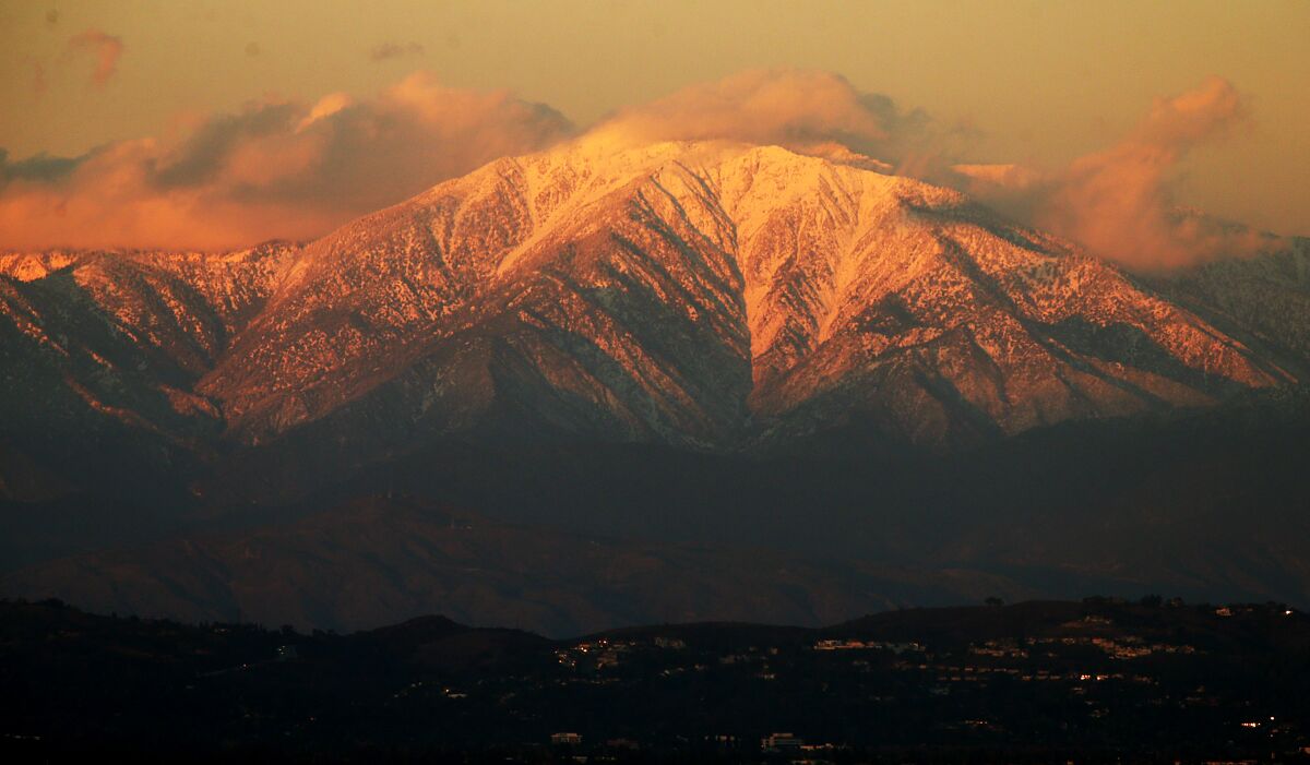 The setting sun casts a golden glow on the snow-covered peaks.