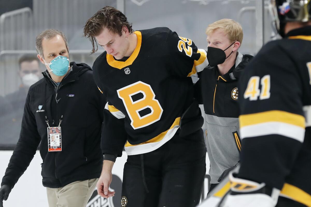 Boston Bruins' Brandon Carlo is helped off the ice after an injury in the first period of an NHL hockey game against the Washington Capitals, Friday, March 5, 2021, in Boston. (AP Photo/Michael Dwyer)