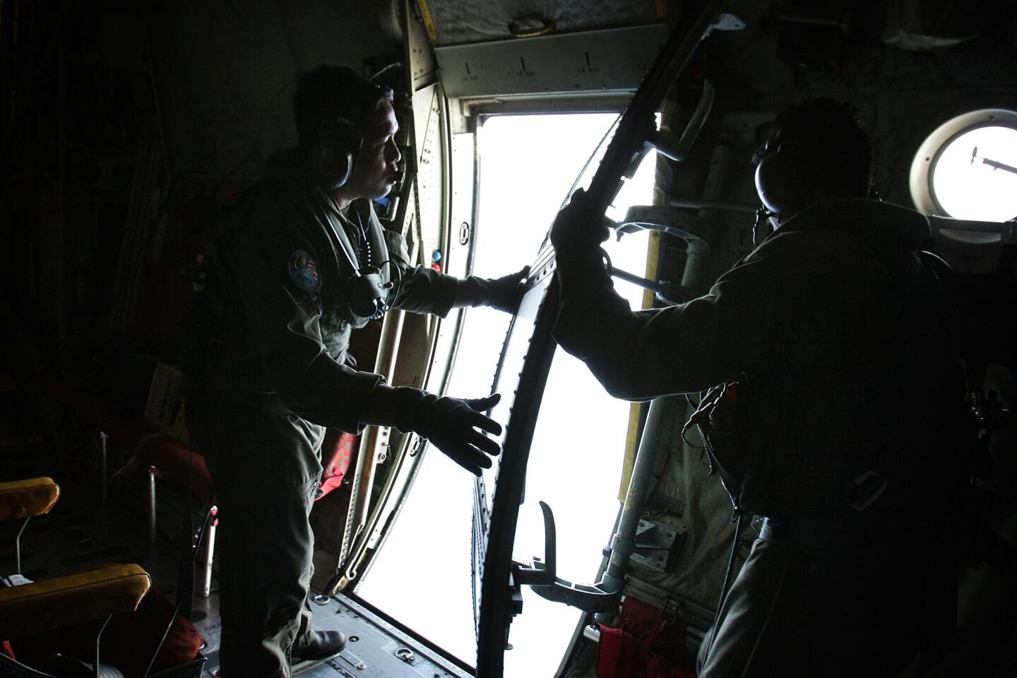Sgt. Zulhelmi Hassan (R) and Sgt. Zul Fahmy (L) of the Malaysian Air Forces close the door for a search and rescue mission flight in Kuala Lumpur, Malaysia.