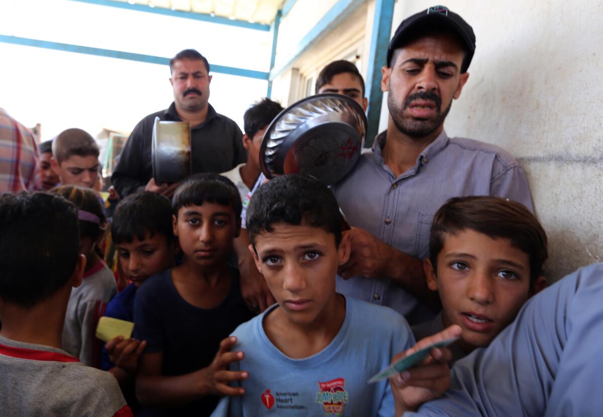 Displaced Iraqis who fled fighting between government forces and the Islamic State group in Anbar province line up to collect donated food at the Alexanzan camp in the Dora neighborhood on the southern outskirts of Baghdad on May 31, 2016.