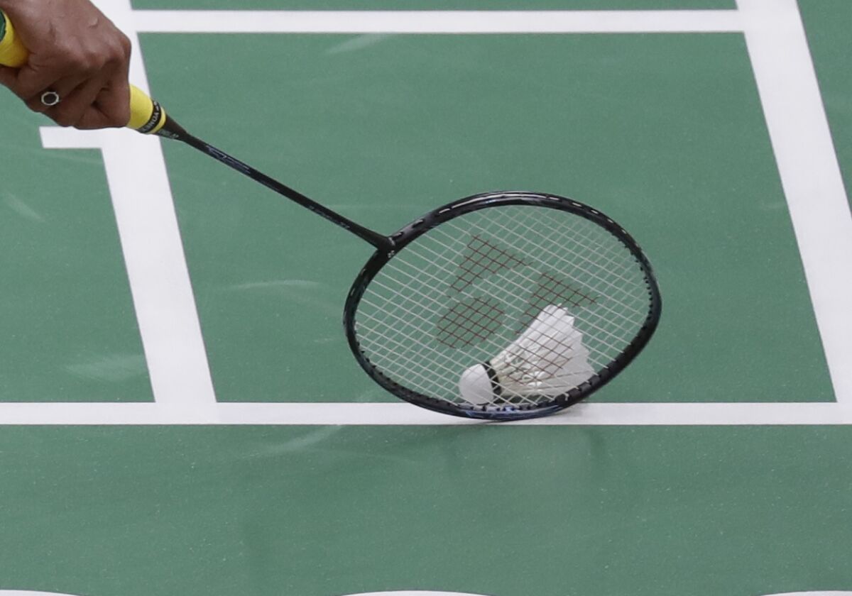 A player picks up the shuttlecock during an Olympic badminton match