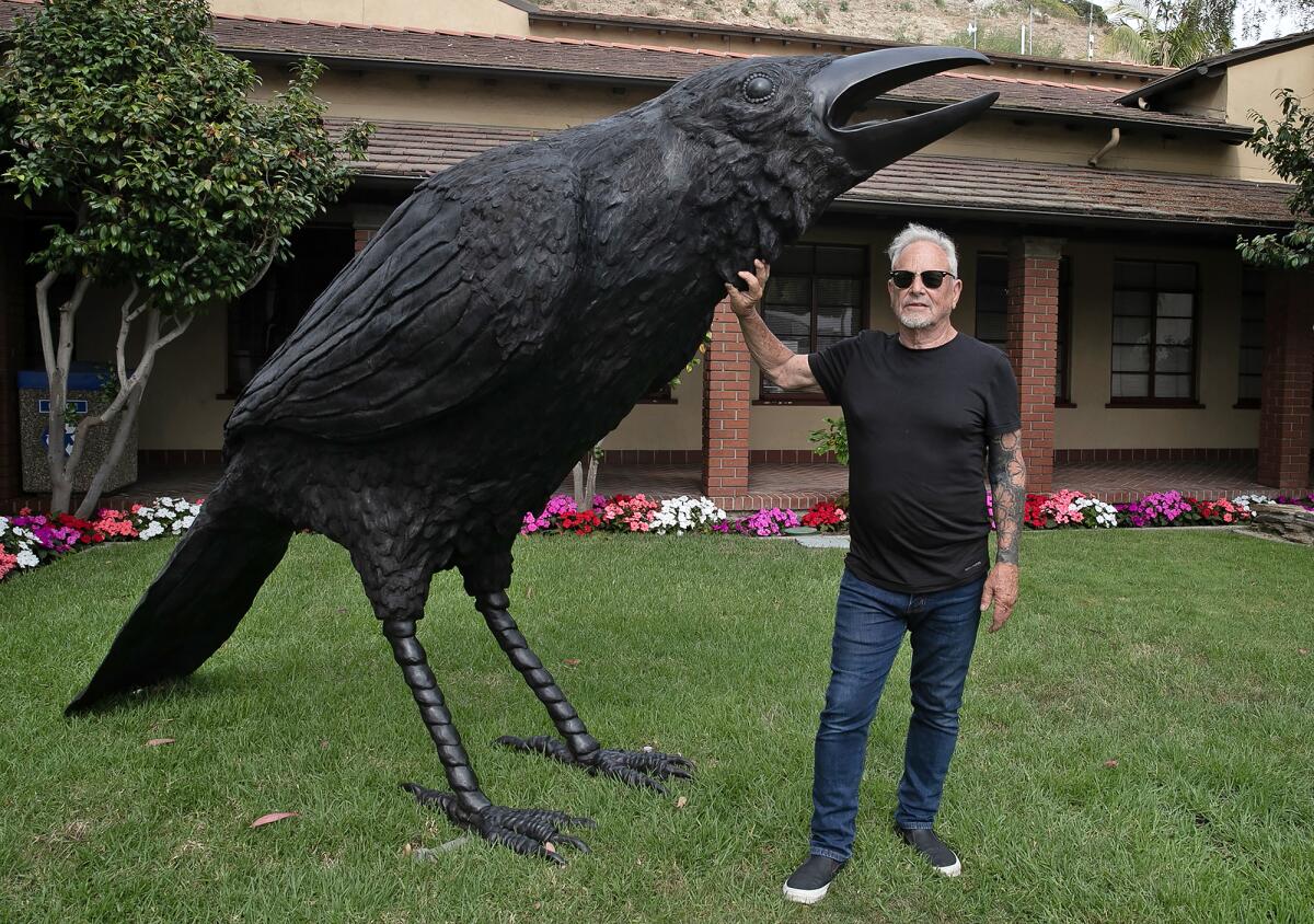 Jack Champion stands with “An Attempted Murder,” a sculpture featuring two bronze crows.