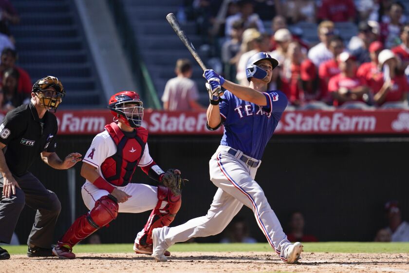 Texas Rangers' Corey Seager, right, hits a home run during the fifth inning of a baseball game against the Los Angeles Angels in Anaheim, Calif., Sunday, Oct. 2, 2022. Marcus Seimen also scored. (AP Photo/Ashley Landis)