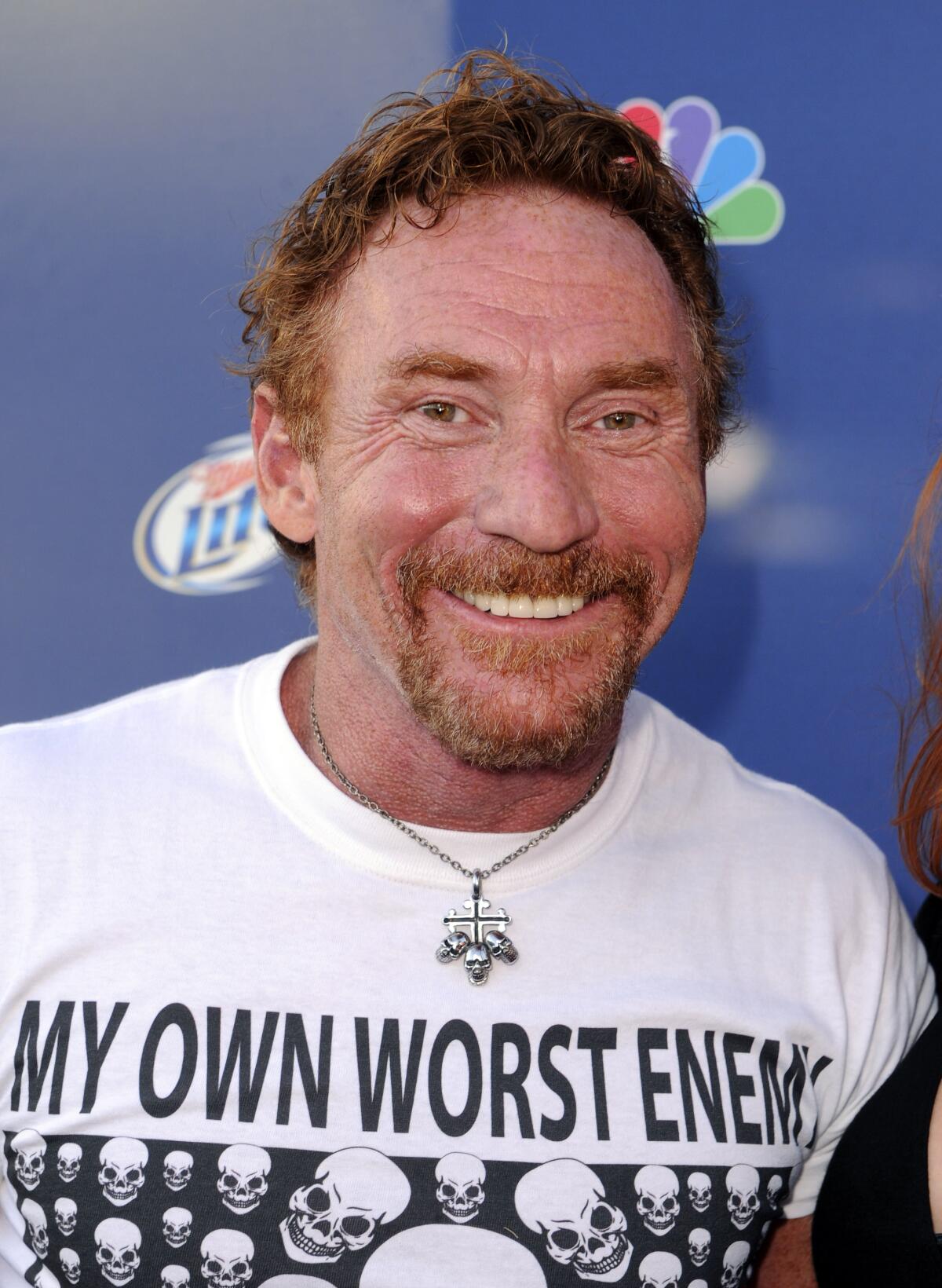 Danny Bonaduce in a white t-shirt that says "My Own Worst Enemy" with skulls and a necklace with a large pendant