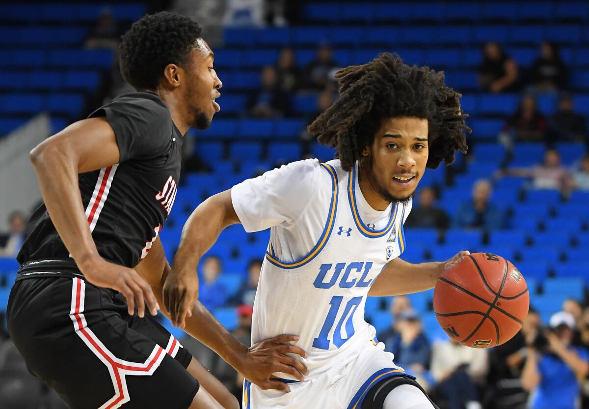 UCLA guard Tyger Campbell, right, tries to drive past Stanislaus State's Ty Davis.