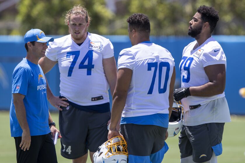 Los Angeles Chargers head coach Brandon Staley, left, talks with offensive tackles Storm Norton.