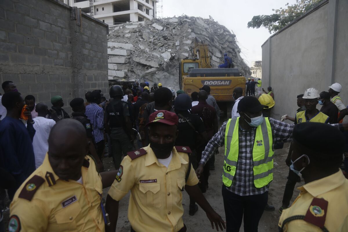 Rescue workers are seen at the site of a collapsed 21-story apartment building under construction in Lagos, Nigeria, Monday, Nov. 1, 2021. At least two people were killed and dozens more remain missing after the collapse of a 21-story apartment building being built in an upscale area of Nigeria's largest city, witnesses said on Monday. (AP Photo/Sunday Alamba)