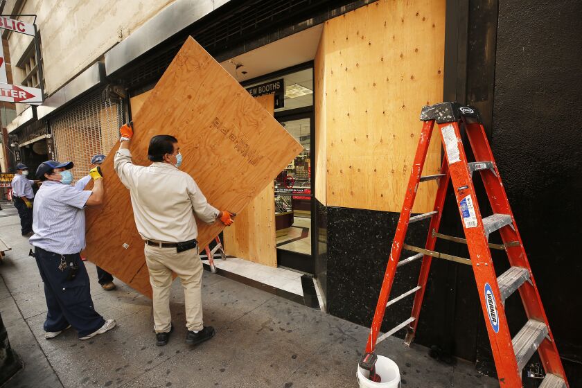 LOS ANGELES, CA - NOVEMBER 02: Workmen build a plywood wall at the storefront of a complex of jewelry stores located at South Broadway and 6th Street in downtown Los Angeles in preparation for possible civil unrest in downtown L.A. as a number of retail store fronts are boarding up in advance of an anxious election day across L.A. on Tuesday. Downtown on Monday, Nov. 2, 2020 in Los Angeles, CA. (Al Seib / Los Angeles Times