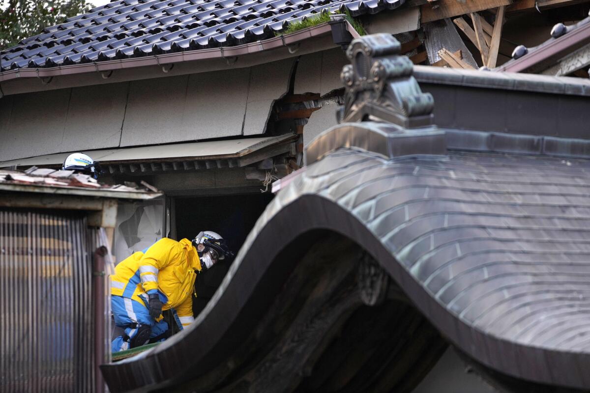 Rescue workers climb into the remains of a building