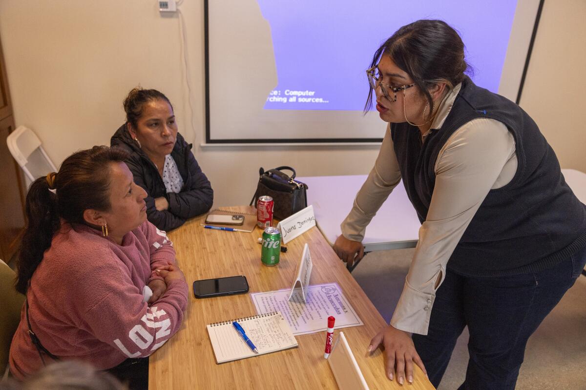 Rosa Vazquez talks with vendors Aurora Alejo and Juana Dominguez during a training for street vendors on Medi-Cal expansion.