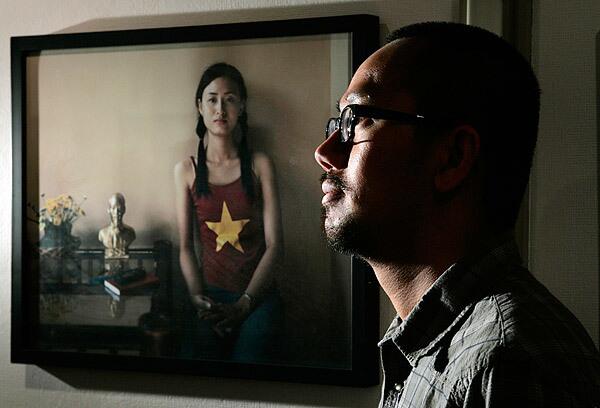 Brian Doan, a photographer, is facing the anger of Vietnamese Americans upset over his picture of a woman wearing a T-shirt with the Vietnamese flag and sitting next to a brass bust of former Communist leader Ho Chi Minh.