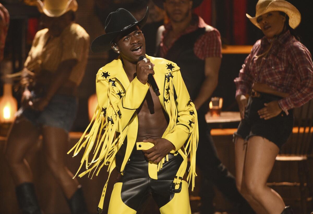 A man in yellow fringe and a cowboy hat performs onstage