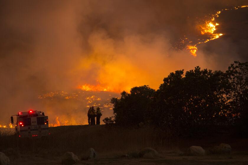 Firefighters gather to observe the Sherpa fire on Thursday as it approaches Highway 101 near Refugio Road in Santa Barbara County.