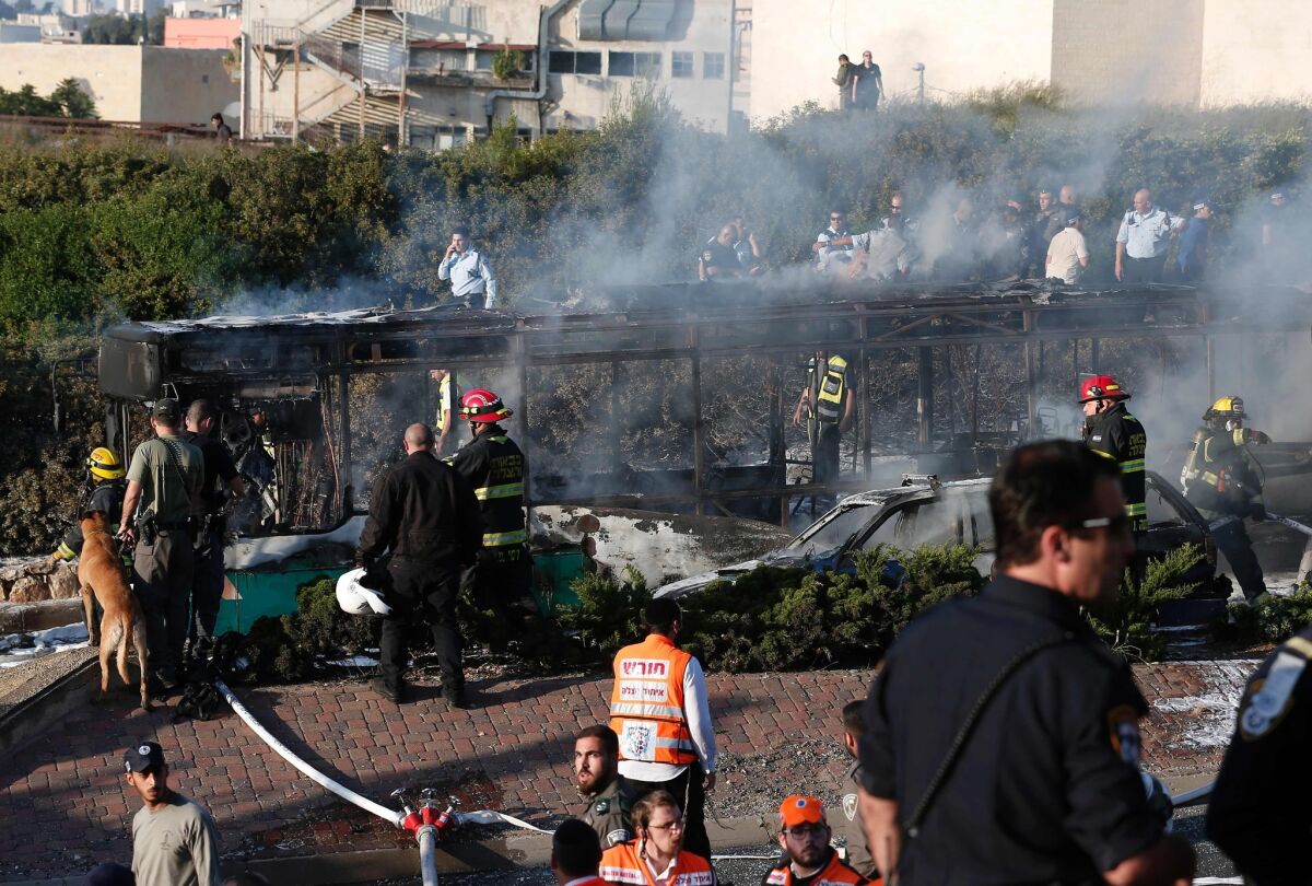 Israeli security forces and emergency services gather around a burned-out bus after an attack in Jerusalem on Monday.